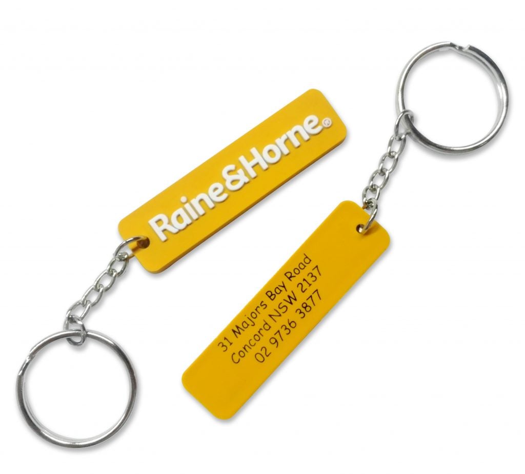 A yellow, double-sided personalised rubber keyring for a real estate business, with a 2D logo on the front and printed details on the back.
