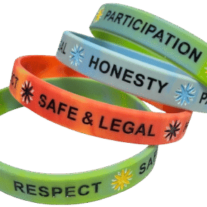A vibrant collection of four custom silicone wristbands in assorted mottled colours (green/yellow, light blue, orange/red), each featuring different personalised printed messages such as 'PARTICIPATION', 'HONESTY', 'SAFE & LEGAL', and 'RESPECT' with starburst symbols, suitable for school awards or awareness initiatives.