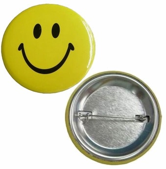 Example of a custom button badge. This branded button badge has a smiley face in black print and yellow background.
