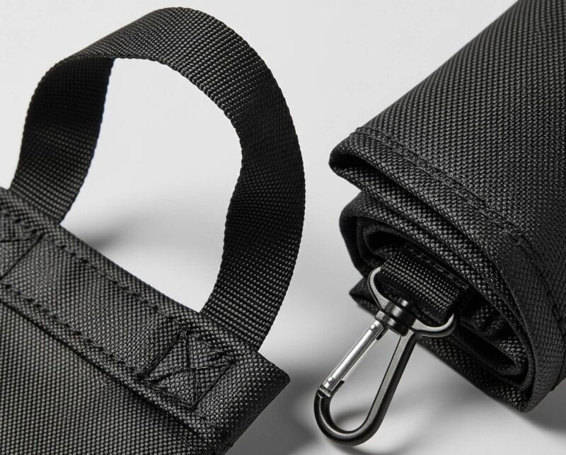 Macro detail shot of a black foldable bag, highlighting the heavy-duty stitching on the handle and the durable ripstop fabric.
