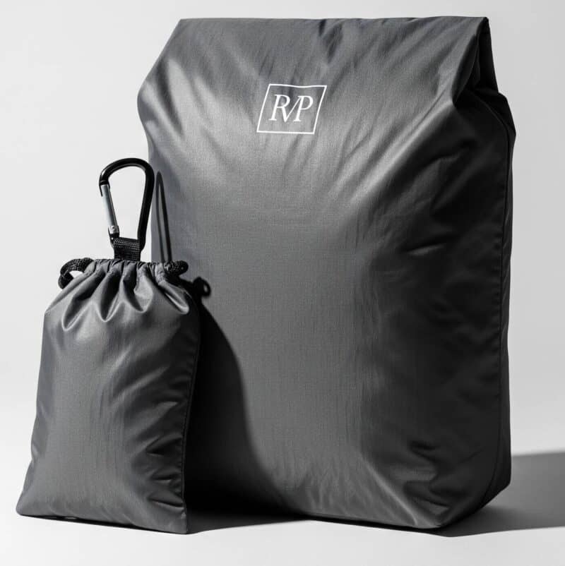 Studio photo of a stylish dark grey foldable shopping bag made from ripstop nylon, shown with its matching storage pouch and carabiner clip.