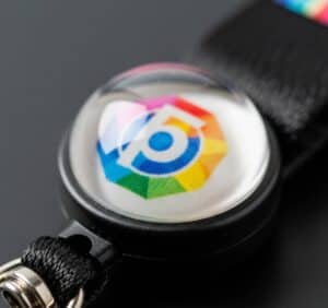 A detailed macro shot of a custom lanyard pull reel, focusing on the glossy, domed epoxy resin that protects the full-colour printed logo.