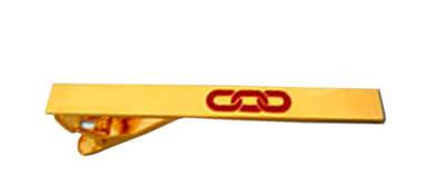 A gold plated tie clip with a simple logo engraved into the metal and filled with red colour.