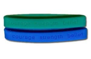 Green and blue personalised silicone wristbands with the words Courage, Strength and Belief engaved into the band.