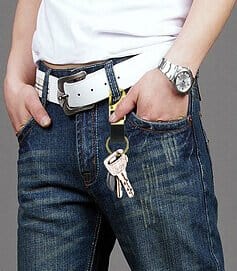This photo is of a man wearing a bottle opener keyring attached to his jeans. He has navy blue jeans and a white belt.
