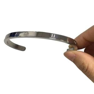 A polished silver stainless steel bracelet with a custom engraved logo on the front plate.