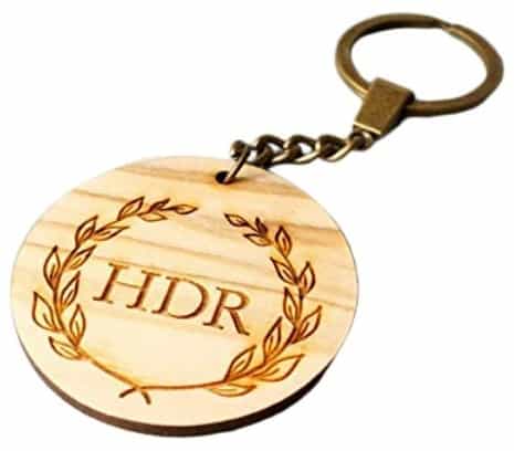 Circle shape custom wooden keyring with basic lettering and tree leaves engraved into the wood.