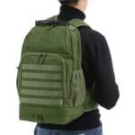 Person wearing view of a camping, hiking, military style outdoor backpack. The material is finished in army style green colour.