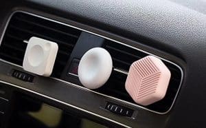 Thress diatomite custom air fresheners pictured connected onto the vent of a car dashboard.