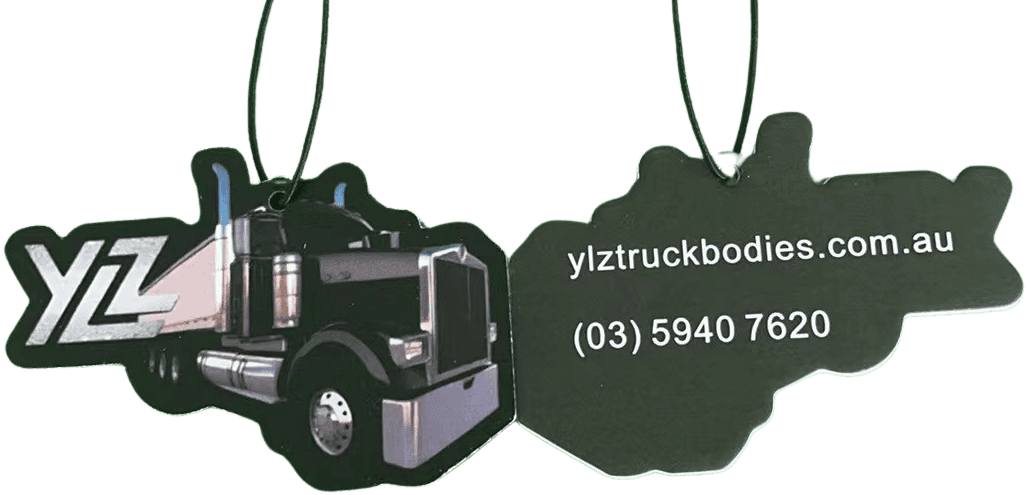 Front and back views of a truck-shaped custom air freshener for 'YLZ Truck Bodies'. The front shows a detailed illustration of a prime mover truck with the 'YLZ' logo. The back is dark with white text displaying the website 'ylztruckbodies.com.au' and phone number '(03) 5940 7620'. Both views show a black hanging string.