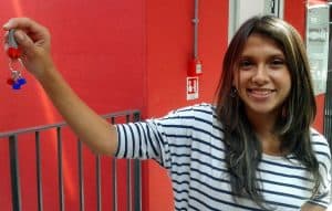 Girl proudly holding up her custom USB keyring in her right hand.