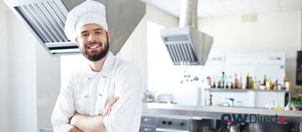Confident chef smiling with arms crossed in a clean and organized commercial kitchen, symbolizing BOH efficiency and professionalism. 
