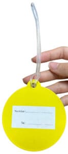 The back of a blank, bright yellow circular rubber ID tag, showing a white panel for writing a number and telephone number.