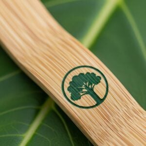 detailed macro shot of a sustainable bamboo lanyard resting on a green leaf, showing the natural wood grain and a cleanly printed green logo.