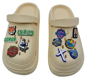 A pair of beige clog-style shoes decorated with custom personalised shoe charms, demonstrating the perfect size and fit for sports teams and school fundraising merchandise.